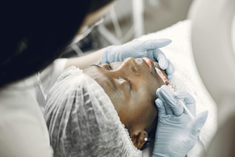 Close-up of a woman receiving a cosmetic lip injection in a clinic setting.